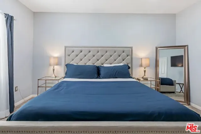 a bed sitting in a bedroom and view of living room