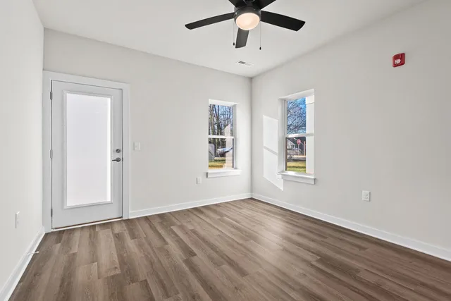a view of an empty room with wooden floor and a window