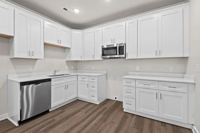 a kitchen with stainless steel appliances granite countertop white cabinets granite counter tops and a hard wood floors