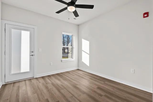 a view of an empty room with a window and wooden floor