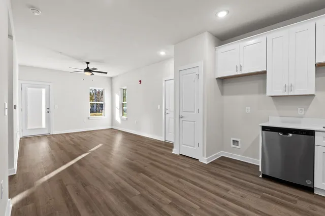 a view of an empty room with wooden floor and cabinets