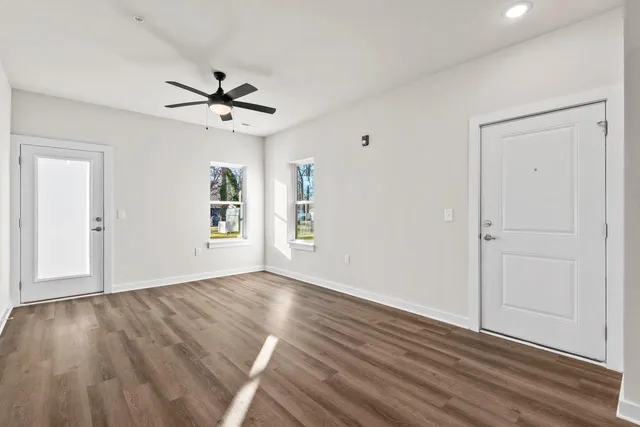 a view of empty room with wooden floor and fan