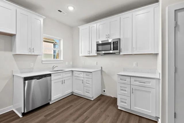 a kitchen with appliances cabinets and a wooden floor