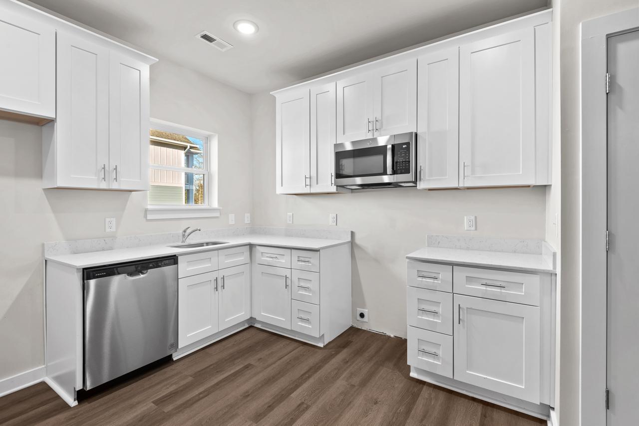 223 South Eleventh Street, Unit 103 Mebane, NC 27302 - Photo 24 of 41 a kitchen with appliances cabinets and a wooden floor