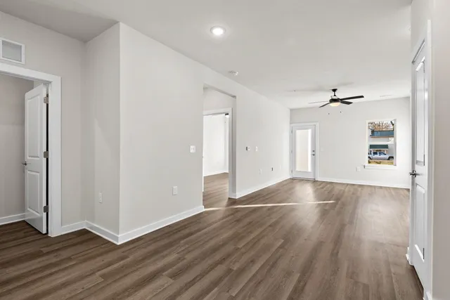 an empty room with wooden floor cabinet and windows