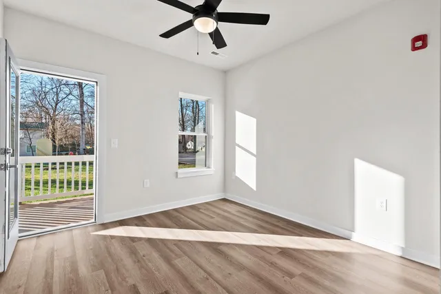 a view of an empty room with a window and wooden floor
