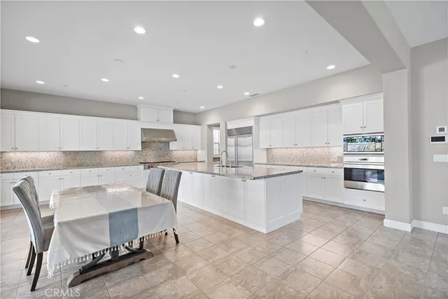 a large white kitchen with a large counter top and stainless steel appliances
