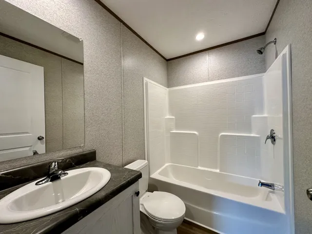 a bathroom with a bathtub shower sink vanity mirror and toilet