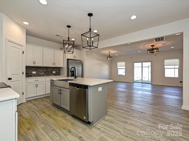 a kitchen with granite countertop a stove top oven a sink dishwasher and white cabinets with wooden floor