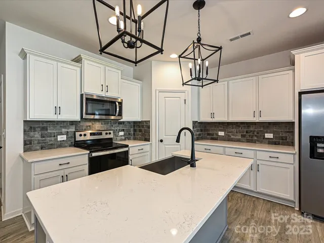 a kitchen with stainless steel appliances a sink a stove top oven a counter space and cabinets