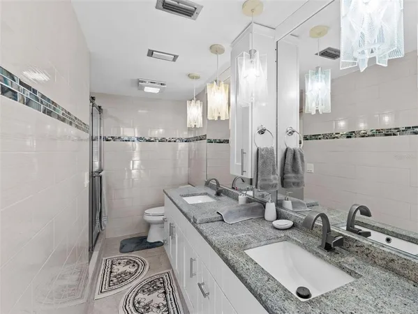 a bathroom with double vanity sinks a toilet a mirror and shower