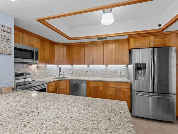 a kitchen with stainless steel appliances granite countertop a refrigerator a stove and a sink with wooden floor