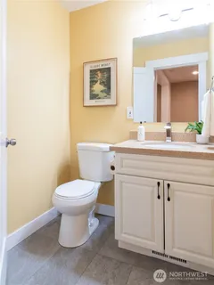 a bathroom with a toilet sink vanity and mirror