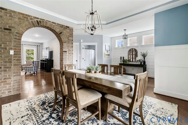 a dining room with furniture a chandelier and wooden floor