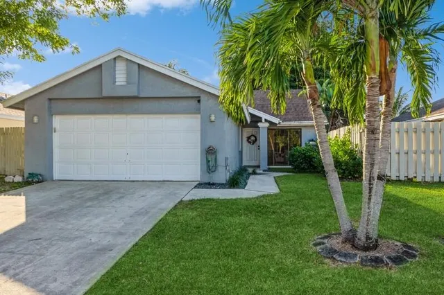 a front view of a house with a yard and large tree