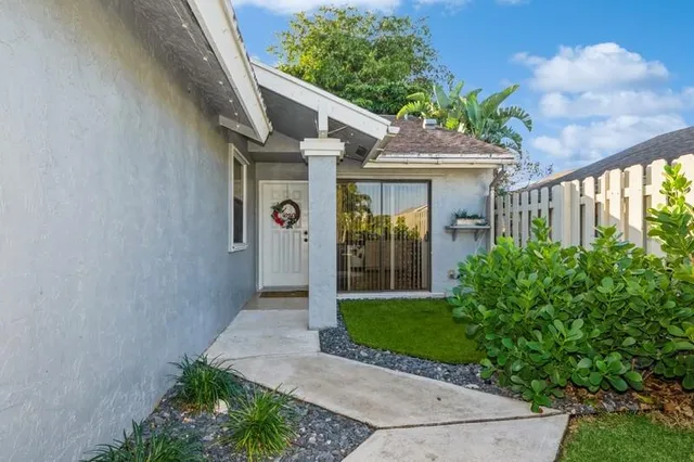 a view of a house with potted plants and a yard