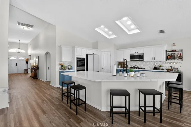 a kitchen with stainless steel appliances a dining table chairs microwave and refrigerator