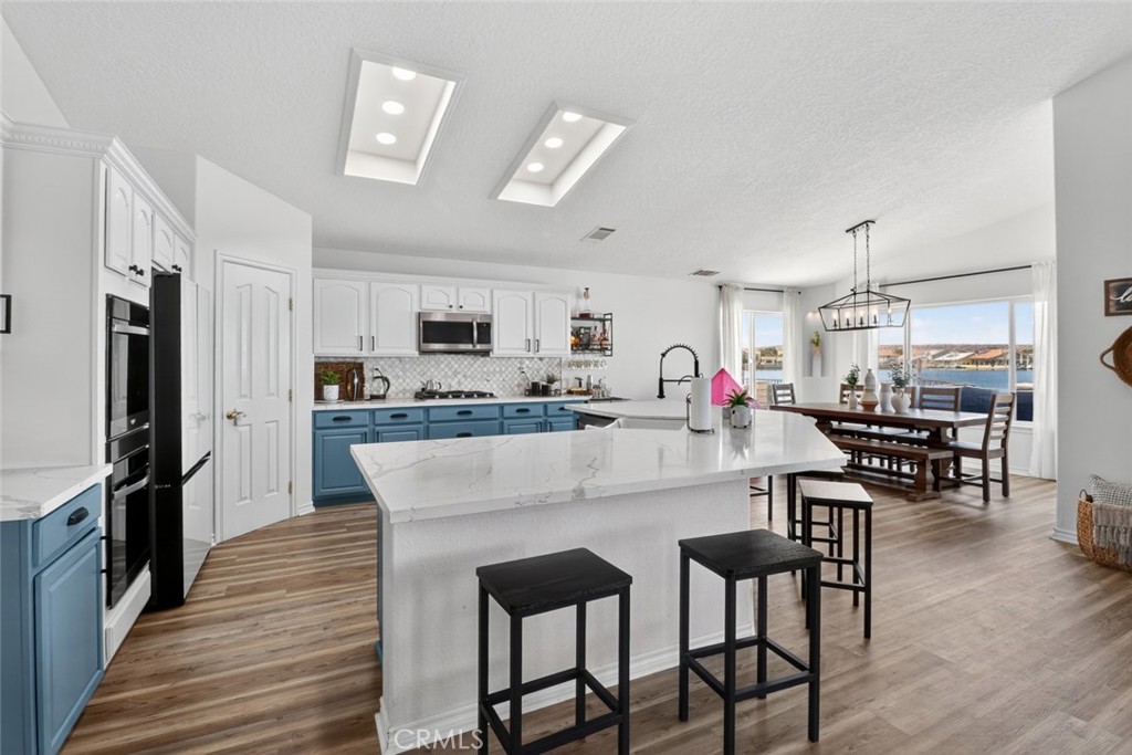 26502 Bluewater Road Helendale, CA 92342 - Photo 16 of 30 a kitchen with stainless steel appliances granite countertop a stove a refrigerator a kitchen island a dining table and chairs with wooden floor