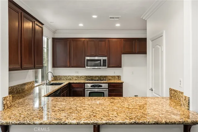 a view of kitchen with stainless steel appliances wooden floor and window