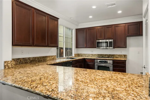 a kitchen with kitchen island granite countertop wooden cabinets and a sink