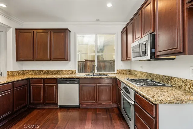 a kitchen with granite countertop a stove top oven microwave and refrigerator