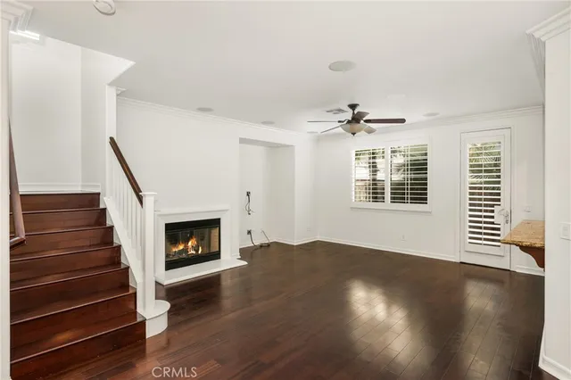 a view of an empty room with wooden floor fireplace and a window