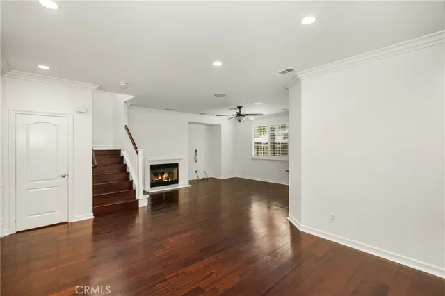 an empty room with wooden floor fireplace and windows