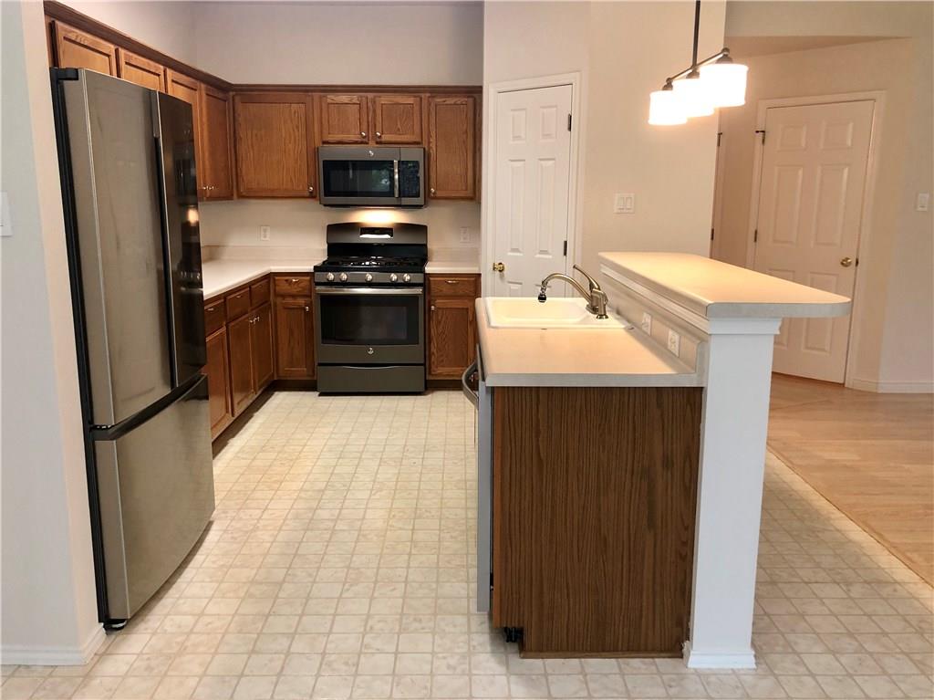 1515 Lochaline Loop Pflugerville, TX 78660 - Photo 2 of 12 Kitchen featuring stainless steel appliances, light countertops, hanging light fixtures, an island with sink, and light flooring