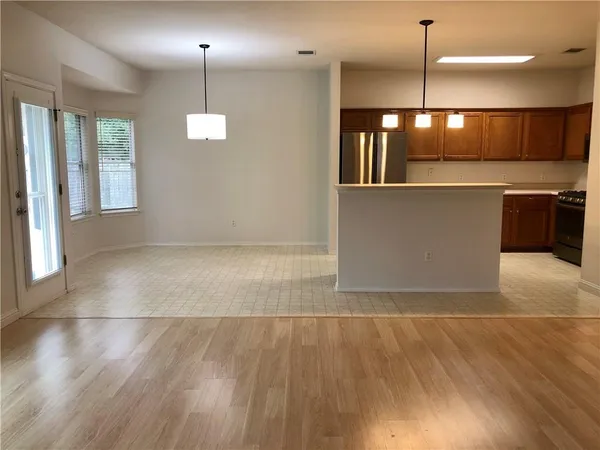 a view of a big room with wooden floor and a kitchen