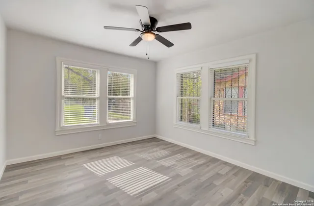 a view of an empty room with a window and wooden floor