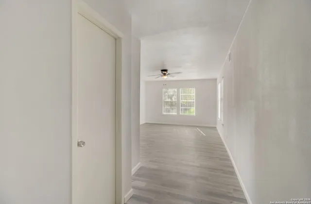 a view of an empty room with wooden floor and a window