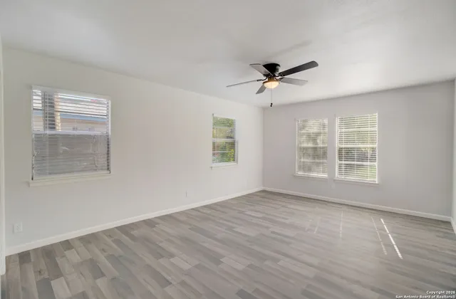 a view of empty room with wooden floor and fan