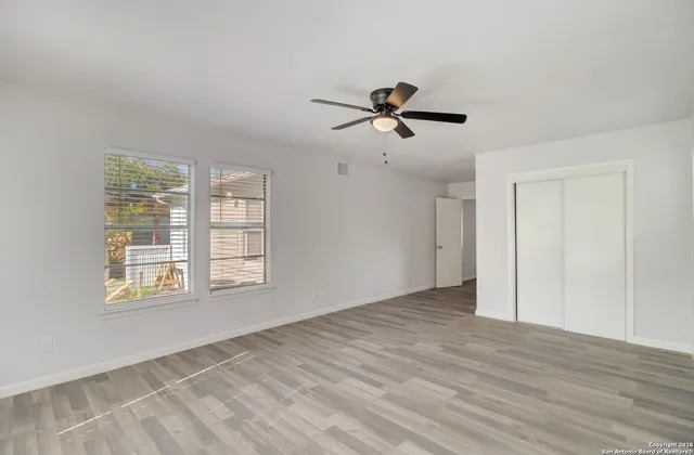 a view of empty room with wooden floor and fan