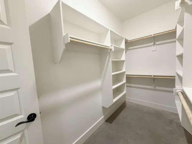 a walk in closet with wooden floor