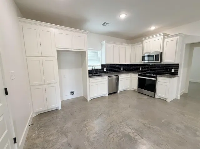 a kitchen with stainless steel appliances granite countertop white cabinets granite counter tops and a wooden floors