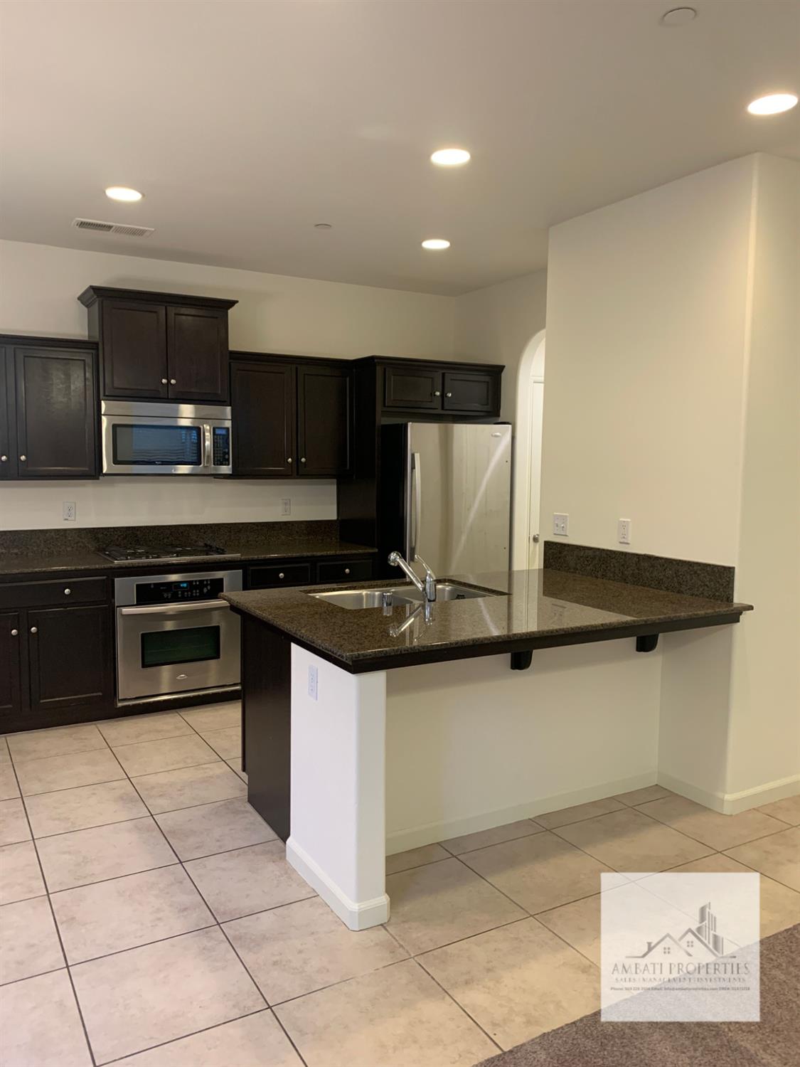 3663 Etchings Way Clovis, CA 93619 - Photo 3 of 26 a kitchen with stainless steel appliances granite countertop a stove a sink and a microwave