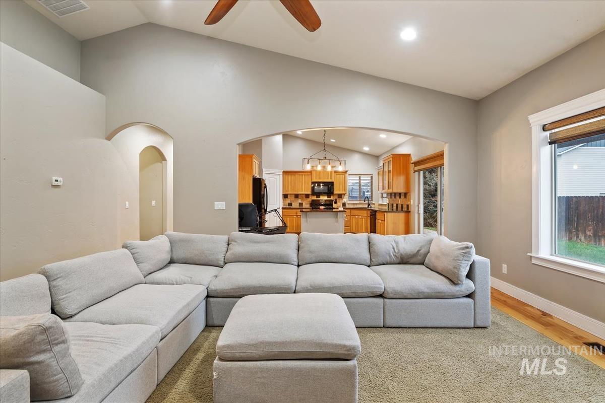 640 Southwest Miner Street Mountain Home, ID 83647 - Photo 13 of 35 Living area featuring lofted ceiling, a ceiling fan, arched walkways, light wood-style floors, and a chandelier