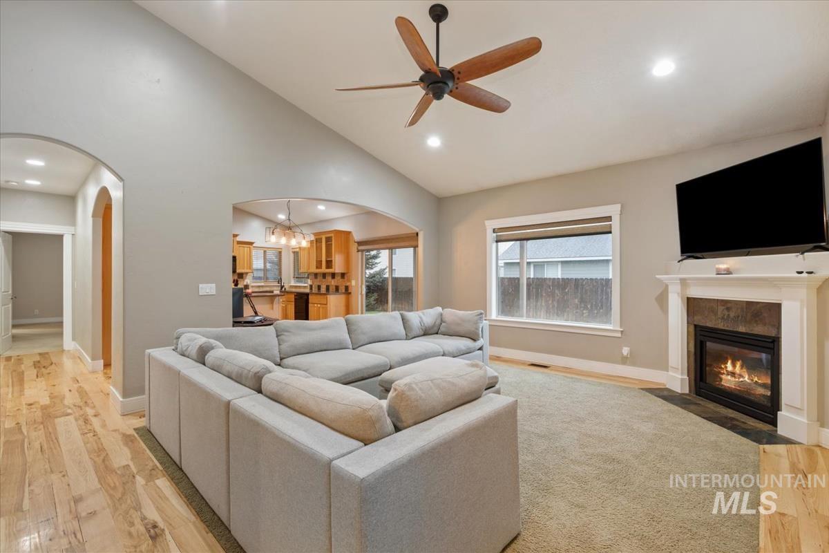 640 Southwest Miner Street Mountain Home, ID 83647 - Photo 15 of 35 Living area featuring light wood-style flooring, a chandelier, a fireplace with flush hearth, ceiling fan, and arched walkways