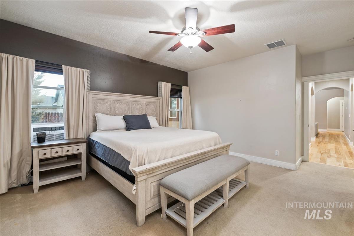 640 Southwest Miner Street Mountain Home, ID 83647 - Photo 25 of 35 Bedroom featuring arched walkways, multiple windows, light colored carpet, a ceiling fan, and a textured ceiling