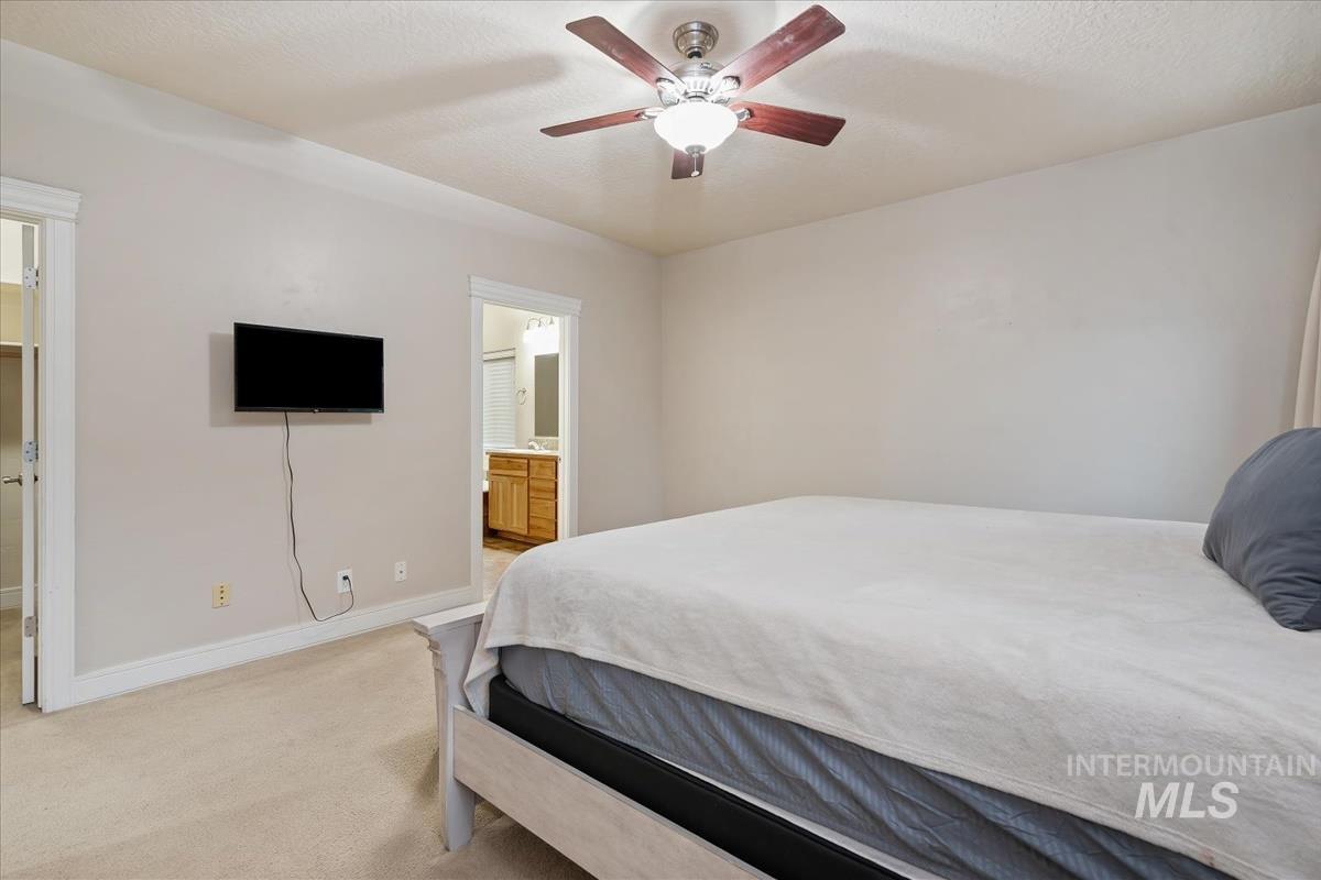 640 Southwest Miner Street Mountain Home, ID 83647 - Photo 27 of 35 Carpeted bedroom with ensuite bath, a ceiling fan, and a textured ceiling