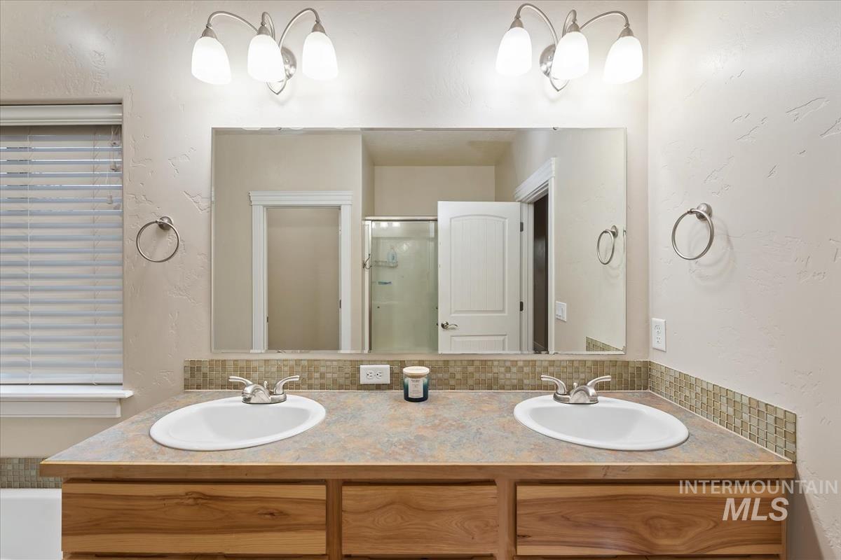 640 Southwest Miner Street Mountain Home, ID 83647 - Photo 29 of 35 Bathroom with a textured wall, double vanity, and a stall shower
