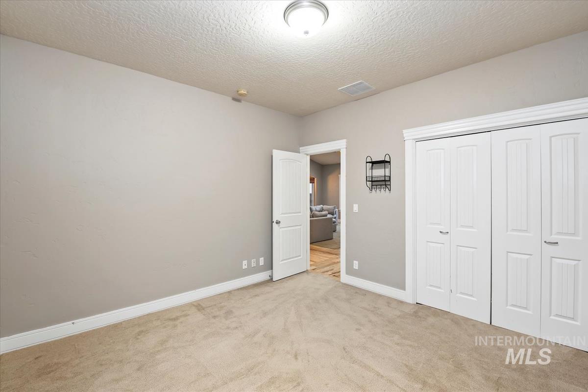 640 Southwest Miner Street Mountain Home, ID 83647 - Photo 5 of 35 Unfurnished bedroom with a textured ceiling, carpet flooring, and a closet