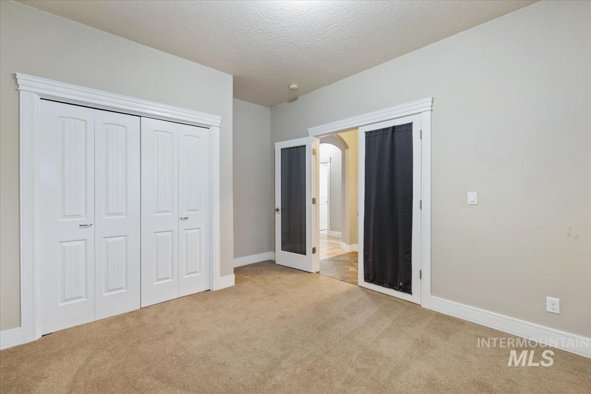640 Southwest Miner Street Mountain Home, ID 83647 - Photo 10 of 35 Unfurnished bedroom with carpet, a textured ceiling, a closet, and french doors