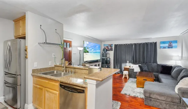a living room with stainless steel appliances kitchen island granite countertop furniture and a refrigerator