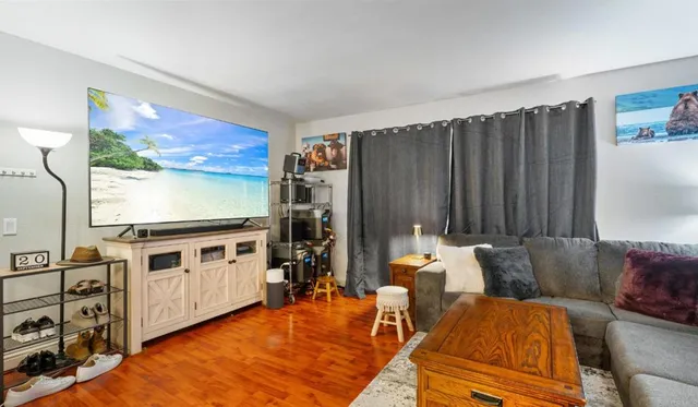 a living room with furniture a flat screen tv and floor to ceiling window