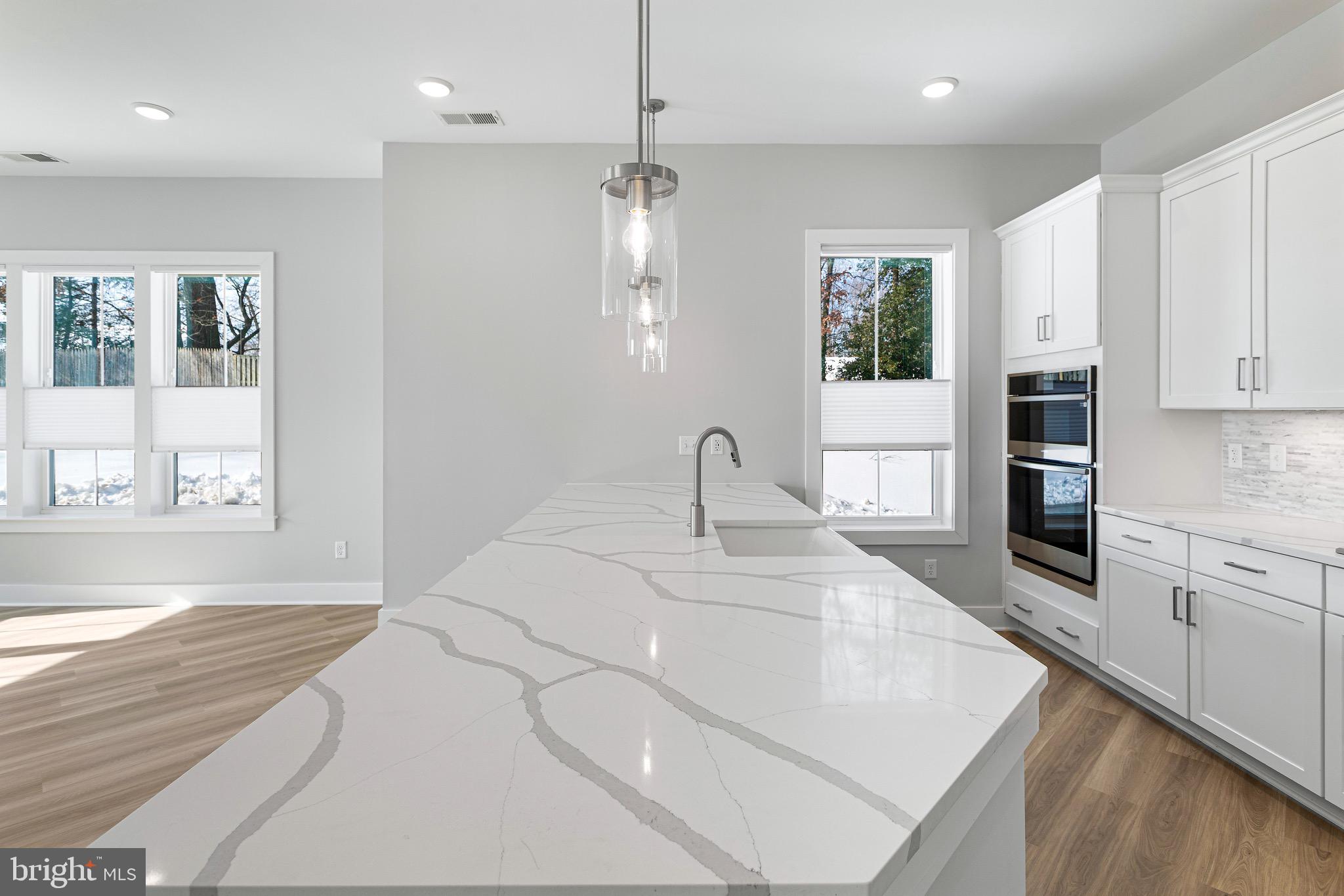 76 Old Mill Bottom Road North, Unit 102 Annapolis, MD 21409 - Photo 21 of 42 a large white kitchen with stainless steel appliances granite countertop a stove a sink dishwasher and a refrigerator with wooden floor