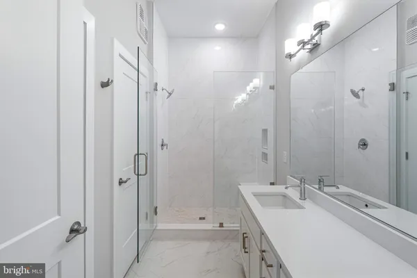 a bathroom with a double vanity sink mirror and shower