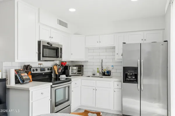 a kitchen with stainless steel appliances a refrigerator sink stove and white cabinets