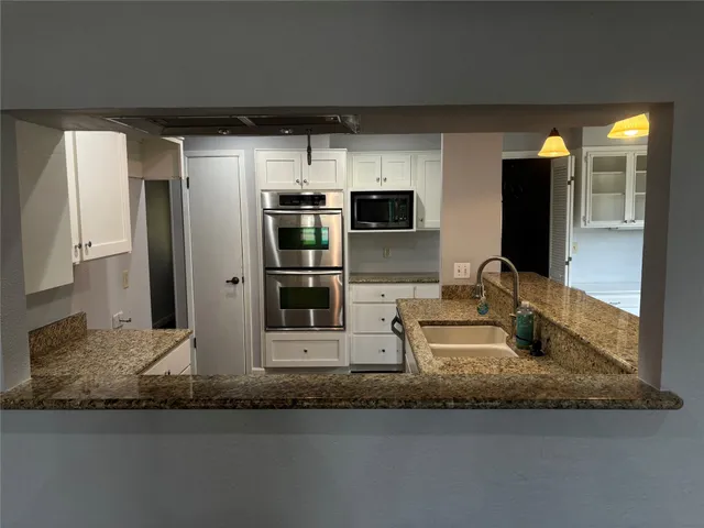 a kitchen with stainless steel appliances granite countertop a sink and a refrigerator