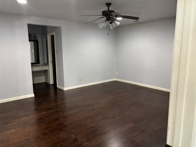 an empty room with wooden floor chandelier fan and closet area